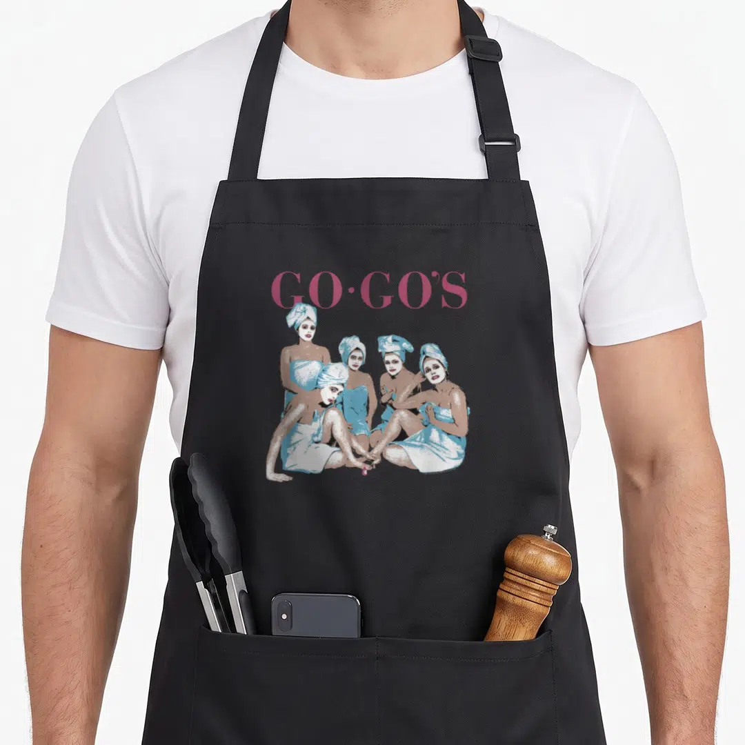 Gos beauty apron - Pink GO-GO'S text above four women in light blue towels and wraps — shown on a black cotton canvas apron against a white background