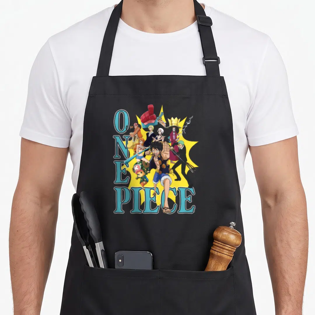 Burst collage anime character apron - One Piece text and Monkey D Luffy group art on yellow starburst — shown on a black cotton canvas apron against a white background