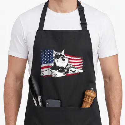 Standard schnauzer apron - White dog silhouette centered on distressed red white and blue American flag pattern — shown on a black cotton canvas apron against a white background