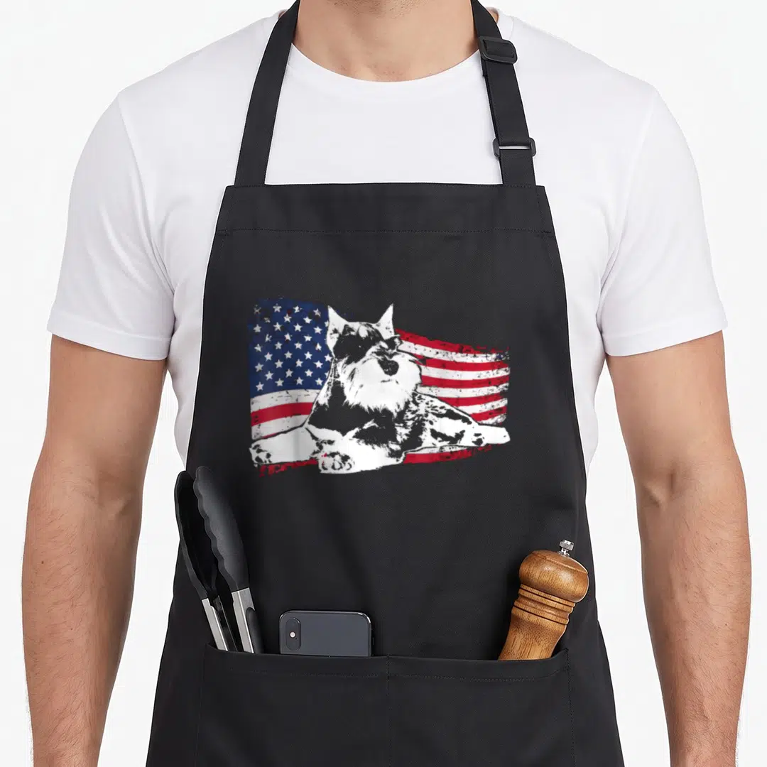 Standard schnauzer apron - White dog silhouette centered on distressed red white and blue American flag pattern — shown on a black cotton canvas apron against a white background