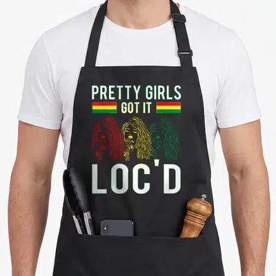 Hair pretty apron - Three women with locs in red yellow green below PRETTY GIRLS GOT IT LOC'D text with two horizontal — shown on a black cotton canvas apron against a white background