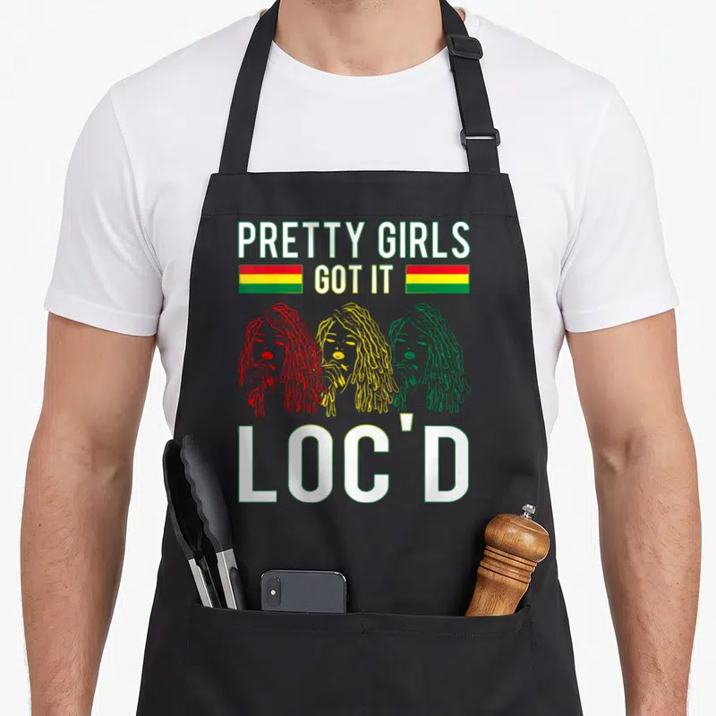 Hair pretty apron - Three women with locs in red yellow green below PRETTY GIRLS GOT IT LOC'D text with two horizontal — shown on a black cotton canvas apron against a white background