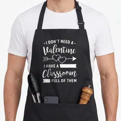 Valentine classroom aprons - I Don't Need A Valentine I Have A Classroom Full Of Them text with arrow and interlocking — shown on a black cotton canvas apron against a white background