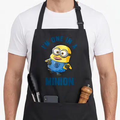 Dave general apron - Cartoon minion character with arched text I'M ONE IN A MINION — shown on a black cotton canvas apron against a white background