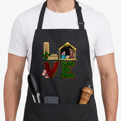 Leopard womens christmas apron - LOVE letters in leopard red and green plaid with nativity scene, holly, and peppermints — shown on a black cotton canvas apron against a white background