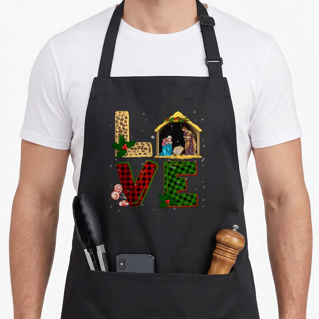 Leopard womens christmas apron - LOVE letters in leopard red and green plaid with nativity scene, holly, and peppermints — shown on a black cotton canvas apron against a white background