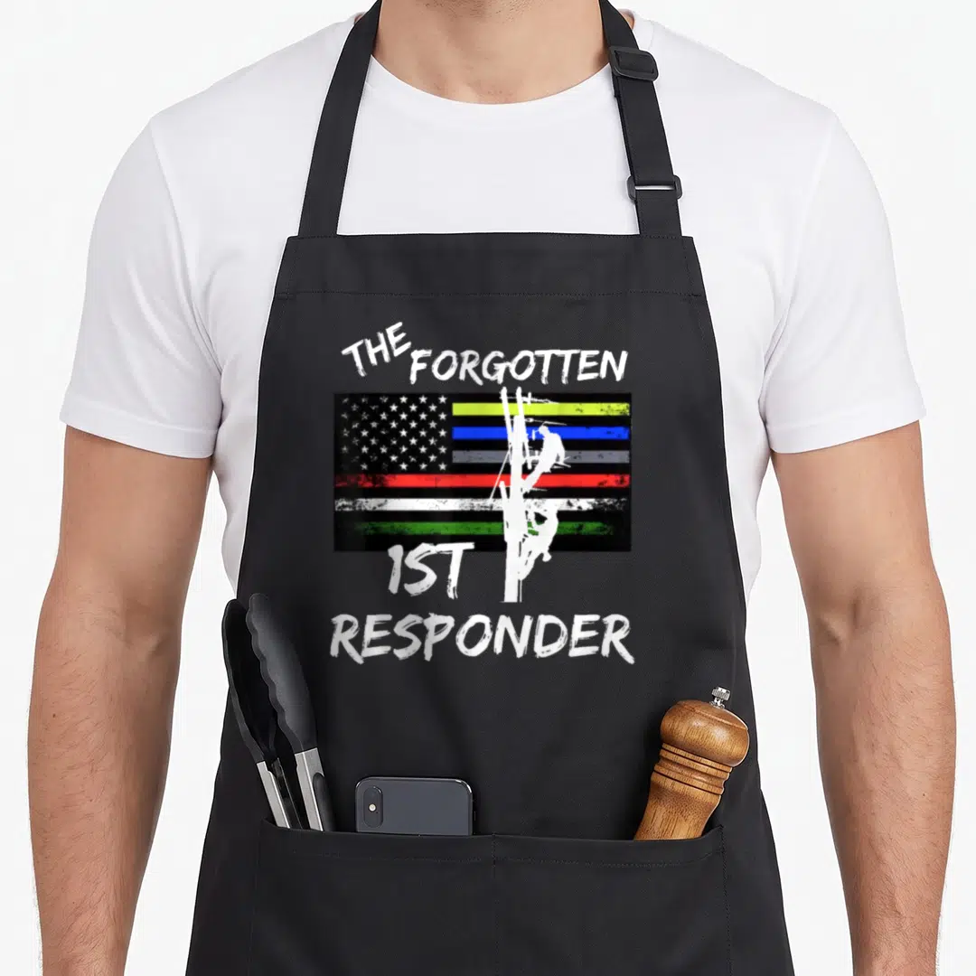Forgotten lineman apron - Distressed text The Forgotten 1st Responder over worker silhouette on multi-color flag — shown on a black cotton canvas apron against a white background