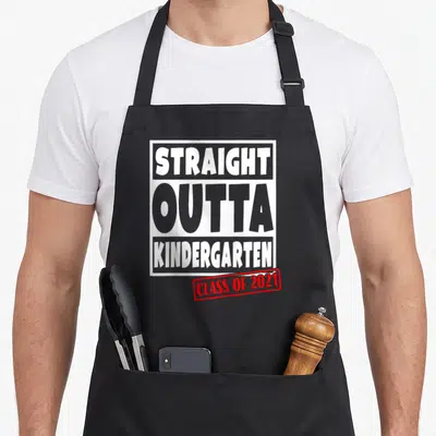 Straight love kindergarten apron - Stacked grey and white text reading Straight Outta Kindergarten with red Class — shown on a black cotton canvas apron against a white background