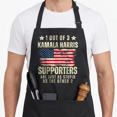 Anti american flag apron - Distressed USA flag with sarcastic text about Kamala Harris supporters flanked by two stars — shown on a black cotton canvas apron against a white background