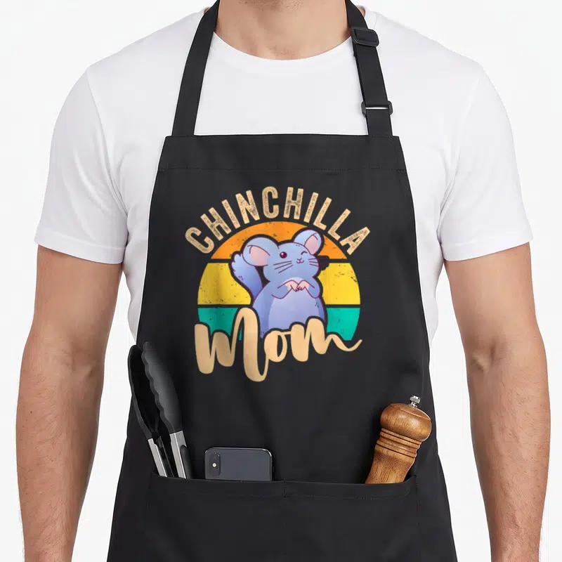 Chinchilla mom apron for women - Blue cartoon chinchilla sitting before striped sunset circle with beige text — shown on a black cotton canvas apron against a white background