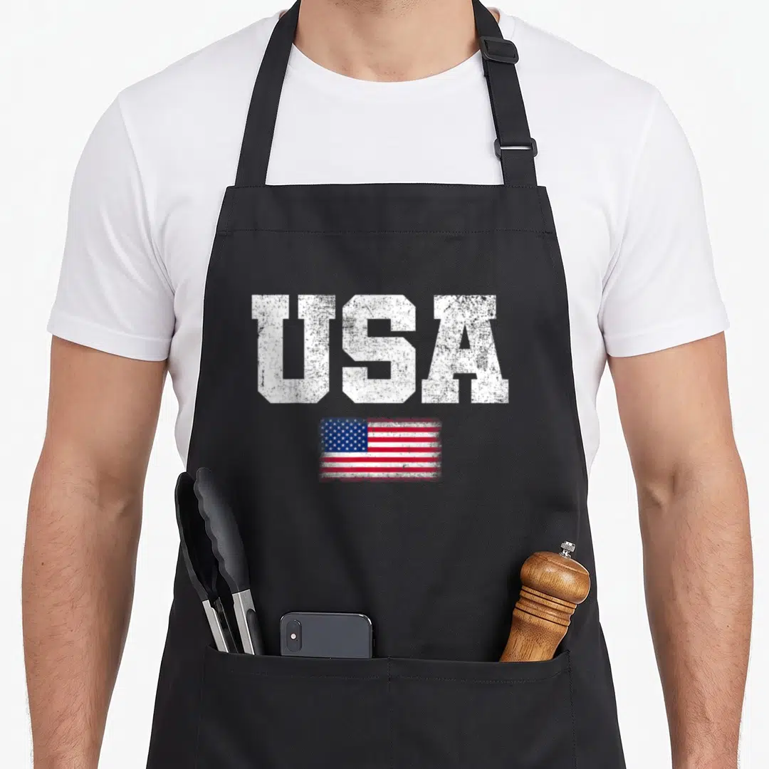 Retro patriotic 4th of july apron - Distressed white USA text above a small red white and blue American flag on an apron — shown on a black cotton canvas apron against a white background