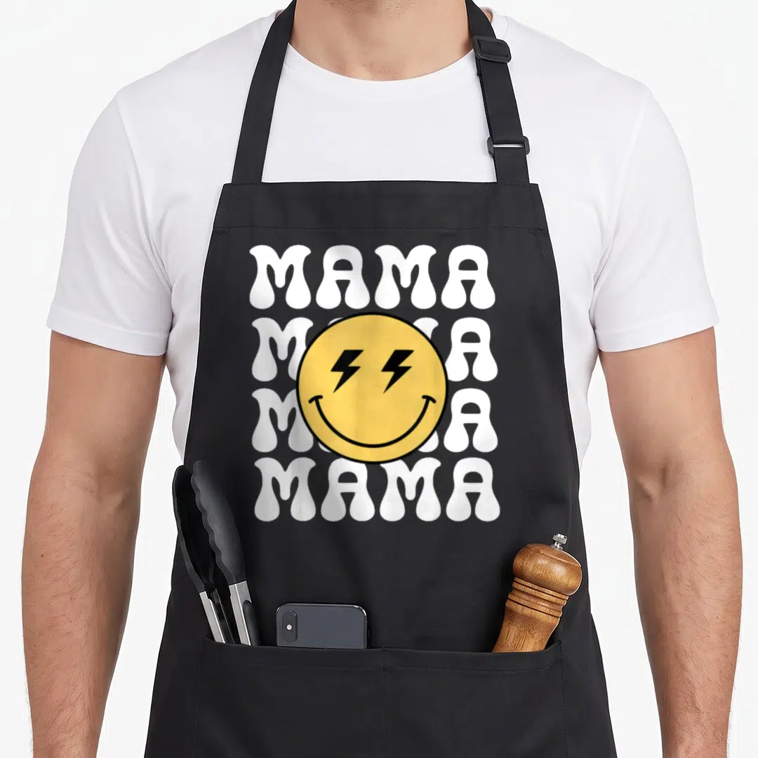Mama custom face apron - Yellow smiley face with lightning bolt eyes over four stacked white MAMA words in retro style — shown on a black cotton canvas apron against a white background