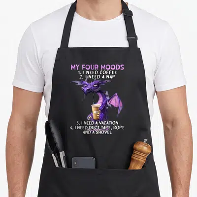 Four coffee apron - Purple cartoon dragon holding coffee cup under text listing four moods ending with tools — shown on a black cotton canvas apron against a white background