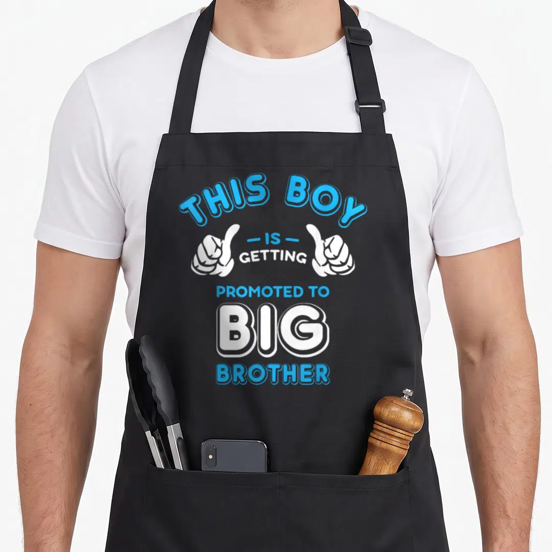 Brother promoted big apron - Vertical text THIS BOY IS GETTING PROMOTED TO BIG BROTHER with two thumbs up hands in blue — shown on a black cotton canvas apron against a white background