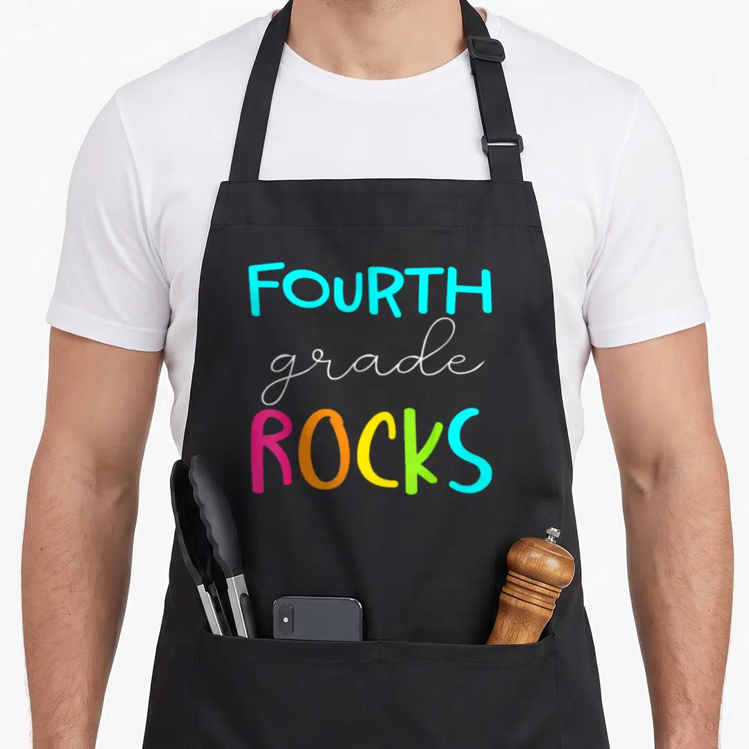 Grade rock teacher apron - Stacked text FOURTH grade ROCKS in cyan white pink orange yellow and green typography — shown on a black cotton canvas apron against a white background