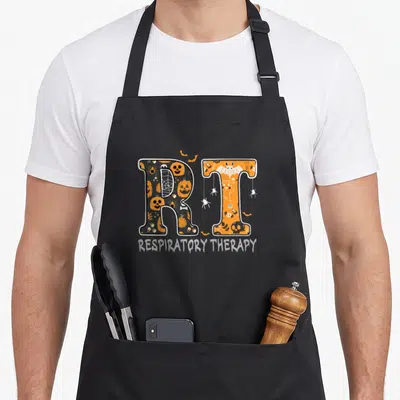 Therapist halloween nurse apron - Large RT letters filled with pumpkins and spiders above RESPIRATORY THERAPY text — shown on a black cotton canvas apron against a white background