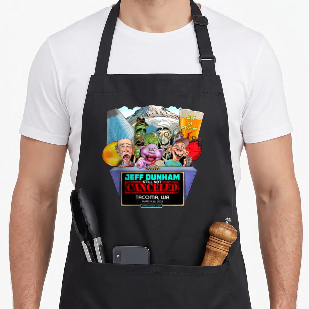 Jeff north boy apron - Jeff Dunham Still Not Canceled Tacoma 2023 cartoon characters grey podium — shown on a black cotton canvas apron against a white background