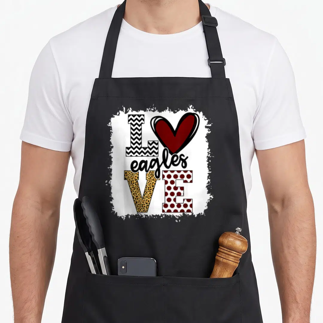 Mascot eagles apron - Heart replacing O in LOVE with patterned letters and centered eagles text in red black white — shown on a black cotton canvas apron against a white background