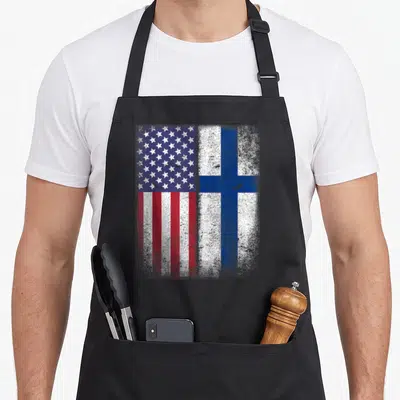 Finnish american flag apron - Two distressed flags side by side, USA on left, Finland on right, blue red white — shown on a black cotton canvas apron against a white background