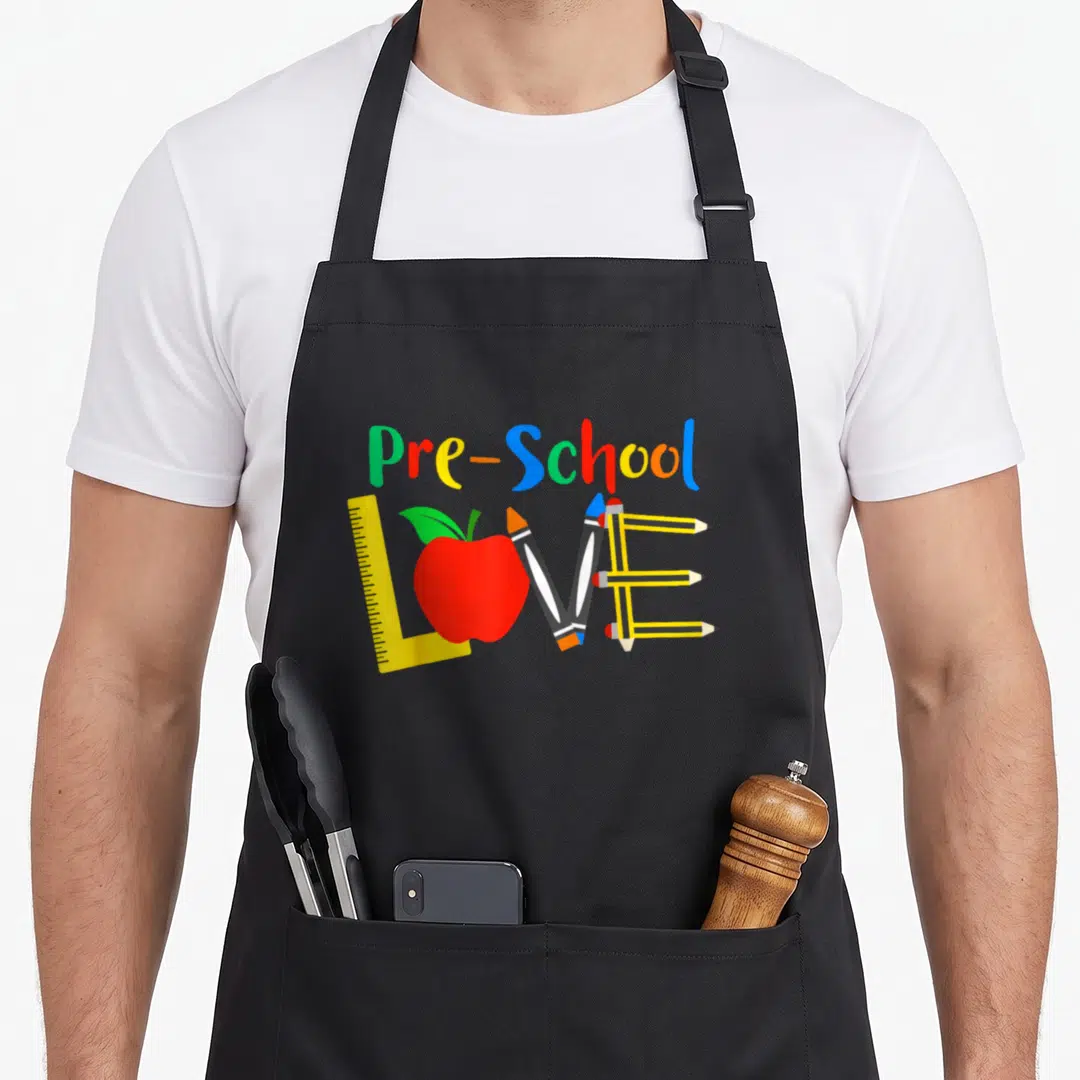 Pre classroom aprons - Pre-School text above LOVE made of ruler, red apple, two pencils, three pencils in red yellow — shown on a black cotton canvas apron against a white background
