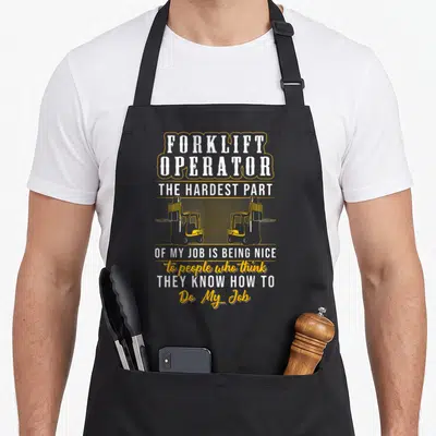 Hardest forklift apron - Forklift Operator sarcastic quote with two facing forklift silhouettes in white and yellow — shown on a black cotton canvas apron against a white background