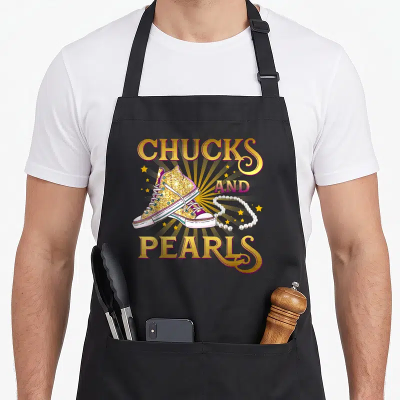 Chuck pearls apron for women - Two gold glitter sneakers and a pearl necklace over a yellow sunburst with printed text — shown on a black cotton canvas apron against a white background