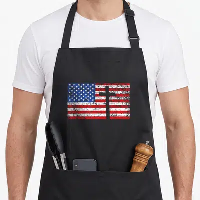 Cross christian american flag apron - Distressed USA flag with superimposed white cross in red, white, and blue — shown on a black cotton canvas apron against a white background