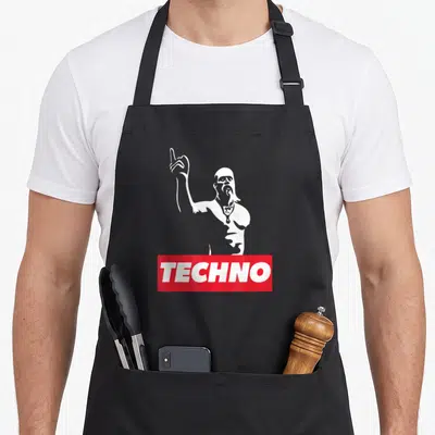 Techno viking apron - White silhouette of a man pointing up above red banner with text TECHNO — shown on a black cotton canvas apron against a white background