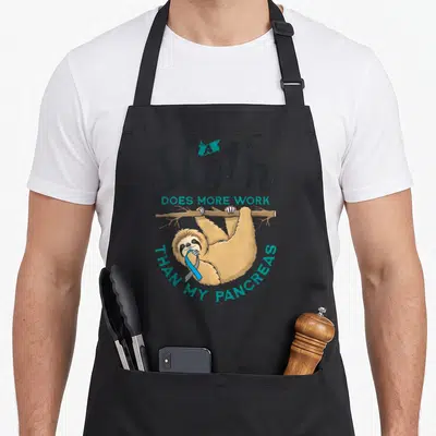 Diabete sloth apron - Cartoon sloth hanging from branch holding blue ribbon with text about pancreas work — shown on a black cotton canvas apron against a white background