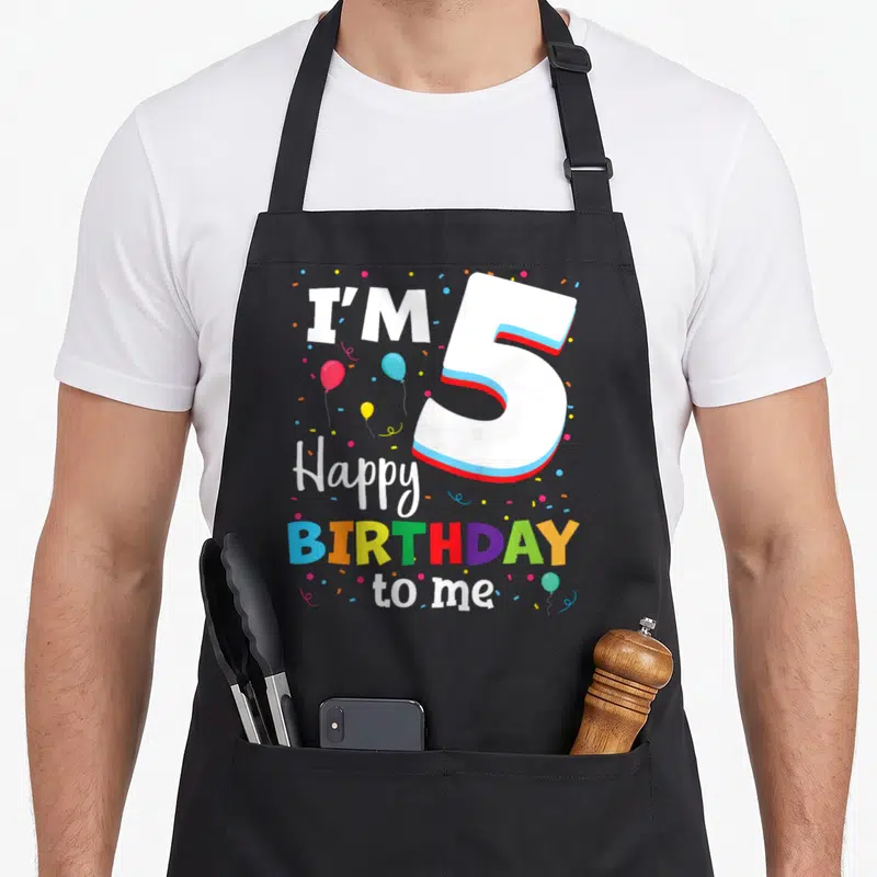 Five birthday apron - Number 5 graphic with I'M 5 Happy BIRTHDAY to me text and colorful balloons — shown on a black cotton canvas apron against a white background