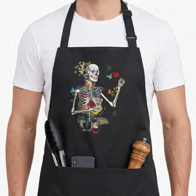 Nature plant apron - Realistic skeleton torso decorated with red, blue, yellow, and off-white flowers and a hummingbird — shown on a black cotton canvas apron against a white background
