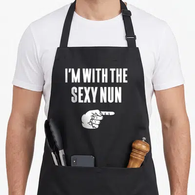 Nun halloween apron - White text I'M WITH THE SEXY NUN above a pointing hand in minimalist style — shown on a black cotton canvas apron against a white background
