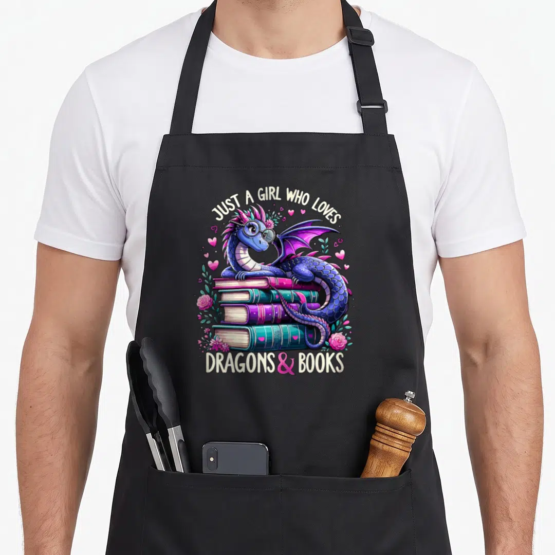 Book dragon apron - Blue dragon with glasses lying on three books surrounded by pink hearts and roses with printed text — shown on a black cotton canvas apron against a white background