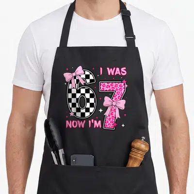 Birthday leopard apron - Number 6 checkerboard and 7 pink leopard print with pink bows and stars — shown on a black cotton canvas apron against a white background