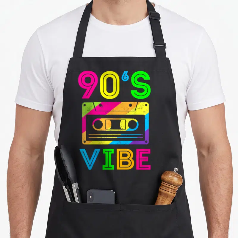 Costume 90s apron - Multi-colored cassette tape with 90'S VIBE text in retro font — shown on a black cotton canvas apron against a white background