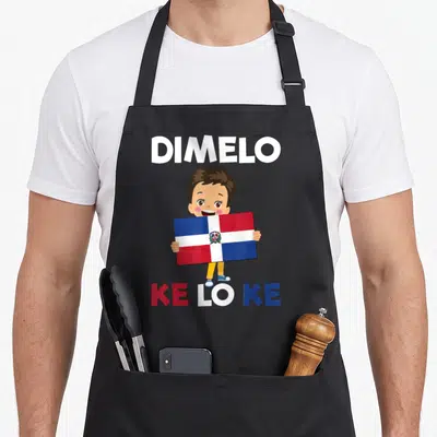 Republic dominican girl apron - Cartoon boy holding Dominican flag with DIMELO KE LO KE text in white red blue brown — shown on a black cotton canvas apron against a white background