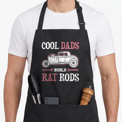 Build rat dad apron - Cool Dads Build Rat Rods text with rat rod side view and two wrenches in white and red distressed — shown on a black cotton canvas apron against a white background