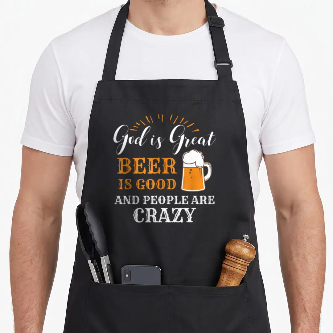 Product beer apron - Stacked white and orange text reading God is Great Beer Is Good next to a beer mug illustration — shown on a black cotton canvas apron against a white background