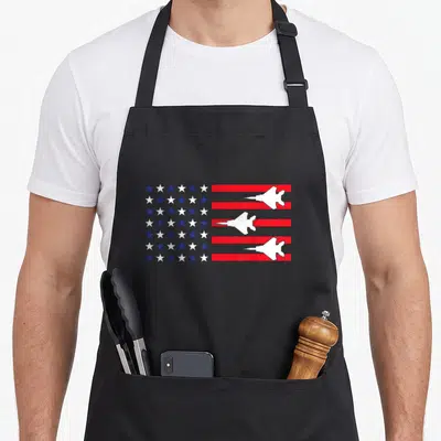 Blue hot sauce apron - Stylized USA flag with three white jets over red and white stripes — shown on a black cotton canvas apron against a white background