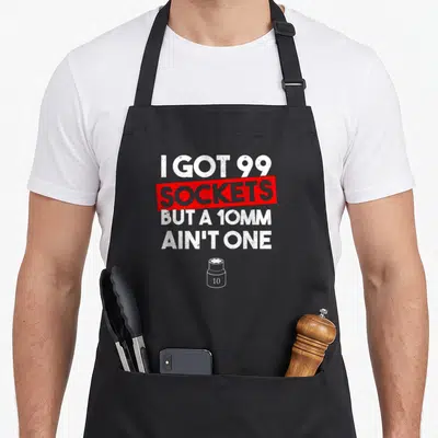 Socket mechanic apron - Distressed text I got 99 sockets but a 10mm ain't one with red box and small socket icon — shown on a black cotton canvas apron against a white background
