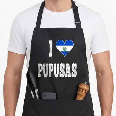 Pupusas salvador el cook apron - I and flag-heart above PUPUSAS text in white distressed font — shown on a black cotton canvas apron against a white background