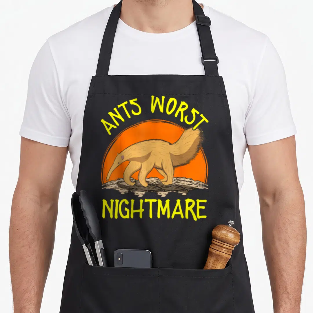 Ant animal apron - Cartoon anteater walking past orange sun with yellow text ANTS WORST NIGHTMARE — shown on a black cotton canvas apron against a white background