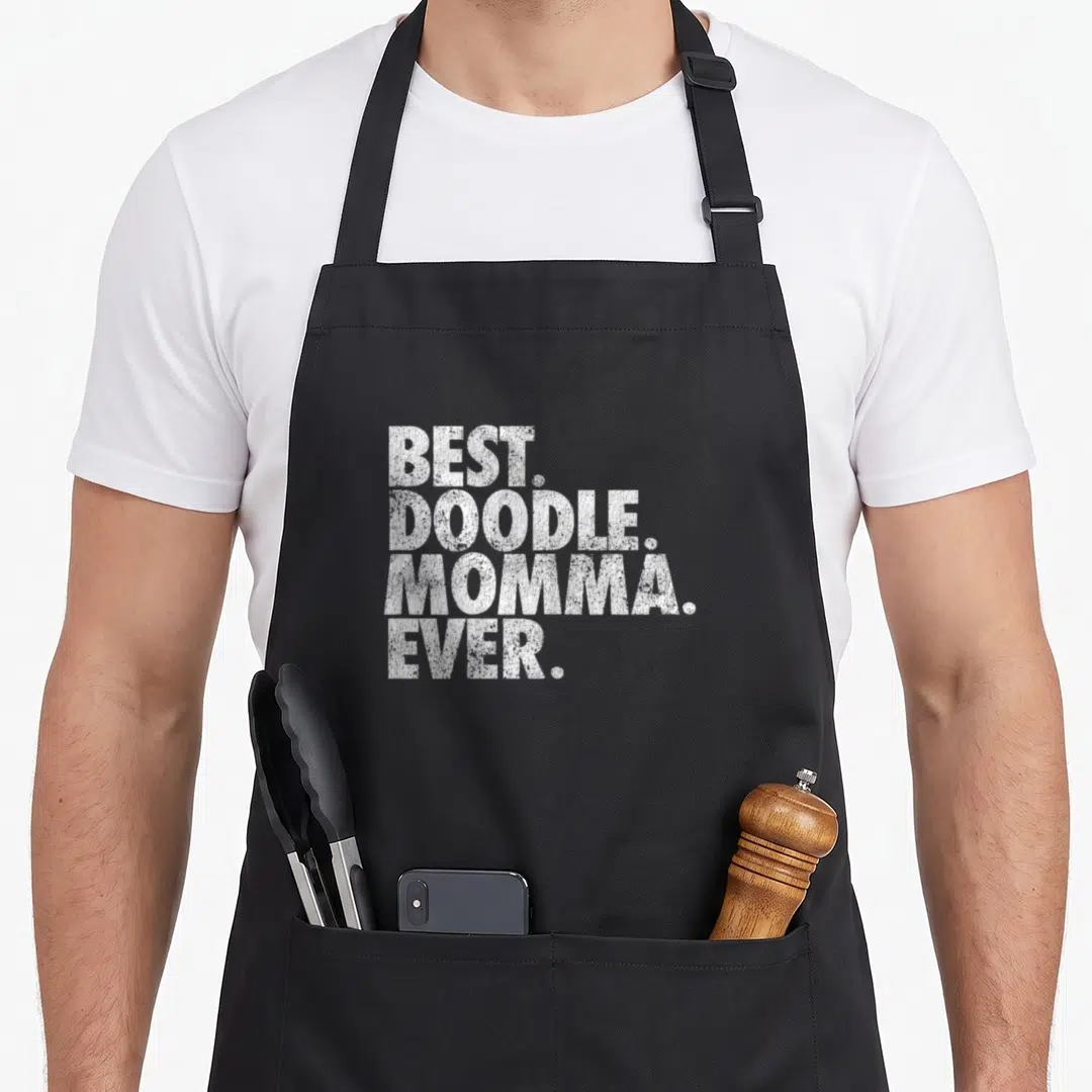 Momma goldendoodle apron - White stacked text reading BEST. DOODLE. MOMMA. EVER. on grey background — shown on a black cotton canvas apron against a white background