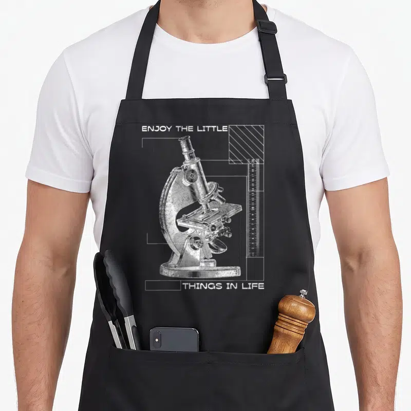 Microscope biology apron - White line-art microscope with ruler and geometric lines on grey background — shown on a black cotton canvas apron against a white background