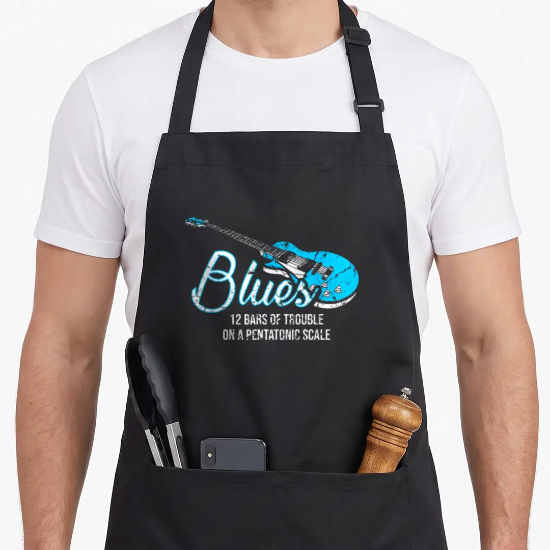 Blue music teacher apron - Distressed blue electric guitar with text 12 bars of trouble on a pentatonic scale — shown on a black cotton canvas apron against a white background