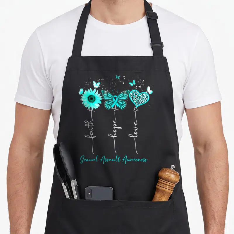 Sexual sunflower apron - Teal sunflower, ribbon butterfly, leopard heart with vertical faith hope love text — shown on a black cotton canvas apron against a white background