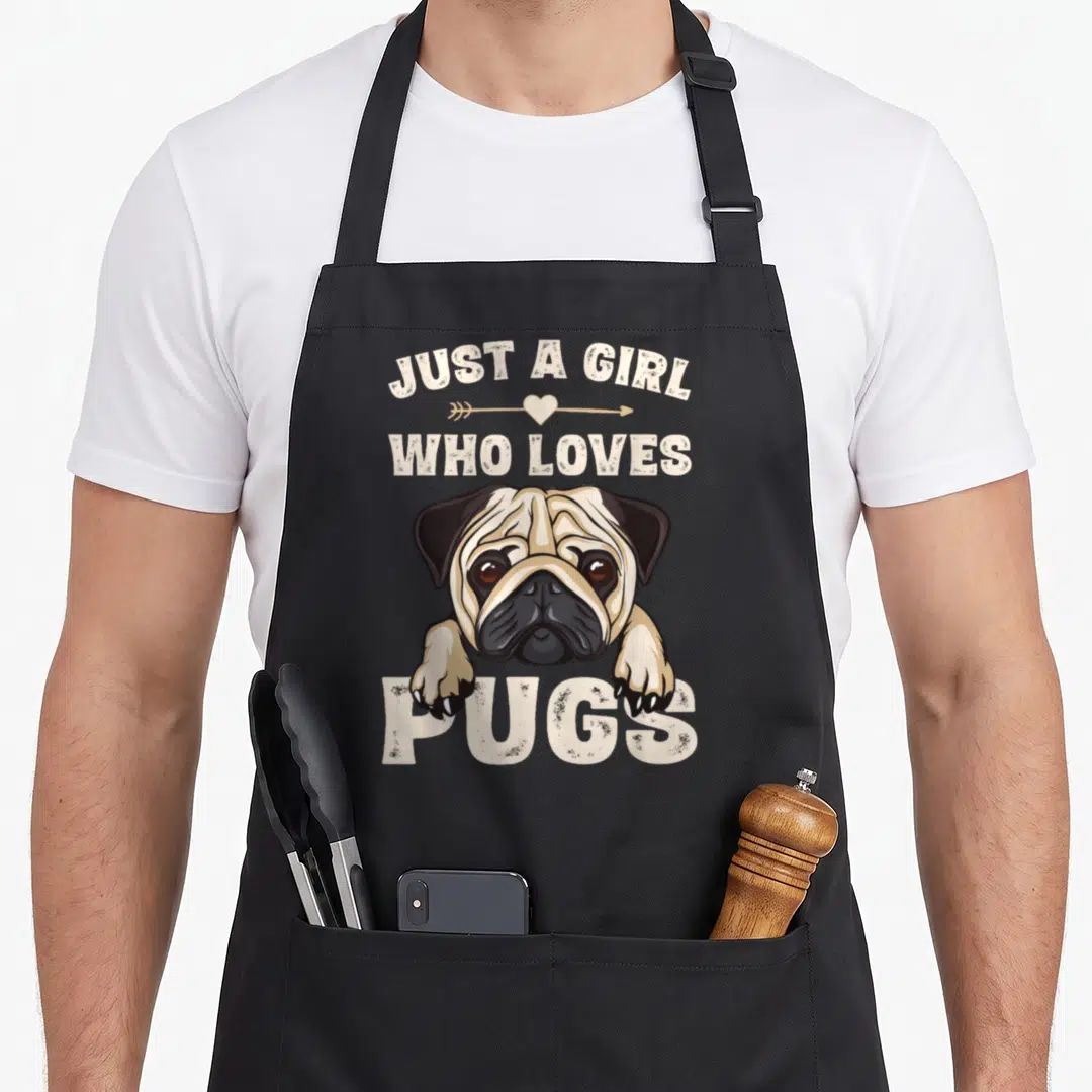 Cool pug dog apron - Just A Girl Who Loves Pugs text with cartoon pug head and paws in beige and black — shown on a black cotton canvas apron against a white background