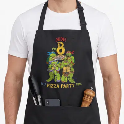 Cute dude pizza apron - Four turtles holding pizza with DUDE I'M 8 text and curved party message below — shown on a black cotton canvas apron against a white background