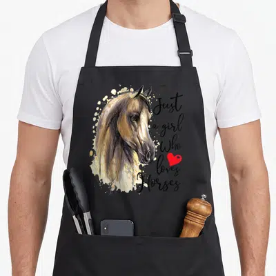 Cool riding horse apron - Realistic horse head with brown mane, black script text, and small red heart symbol — shown on a black cotton canvas apron against a white background