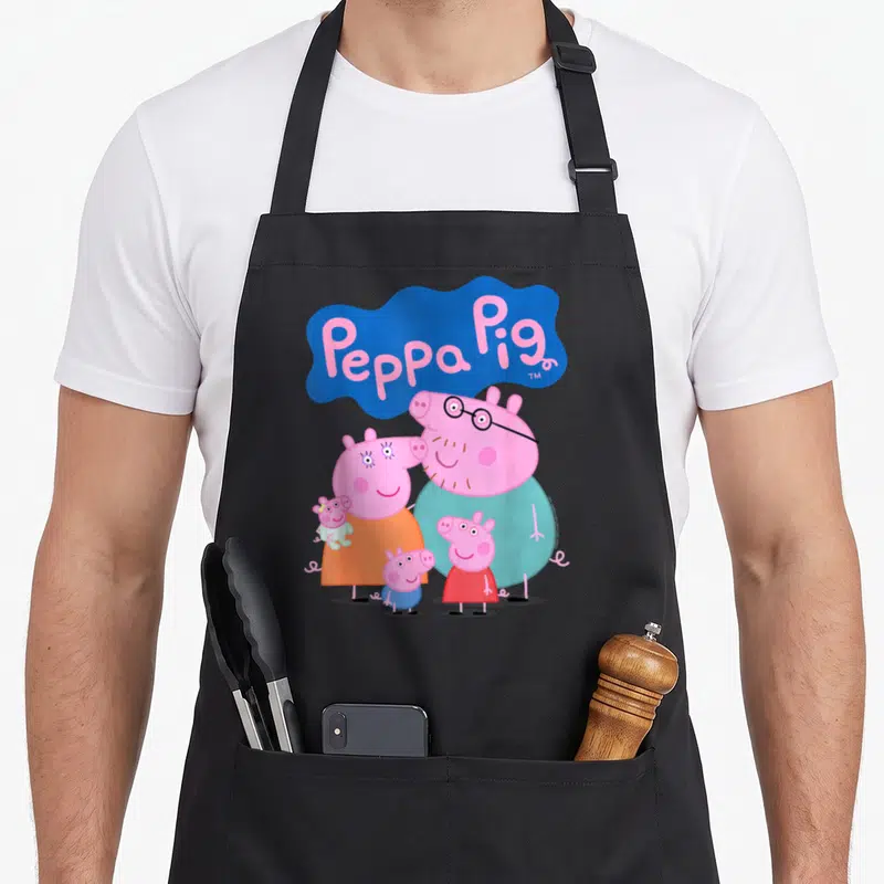 20th family aprons - Peppa Pig family cartoon in pink blue orange red below blue cloud text logo — shown on a black cotton canvas apron against a white background
